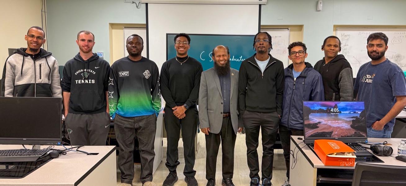 Eight graduates of the bachelor's in computer science degree program stand side by side, smiling alongside CIMST chair Dr. Salam (in the center).