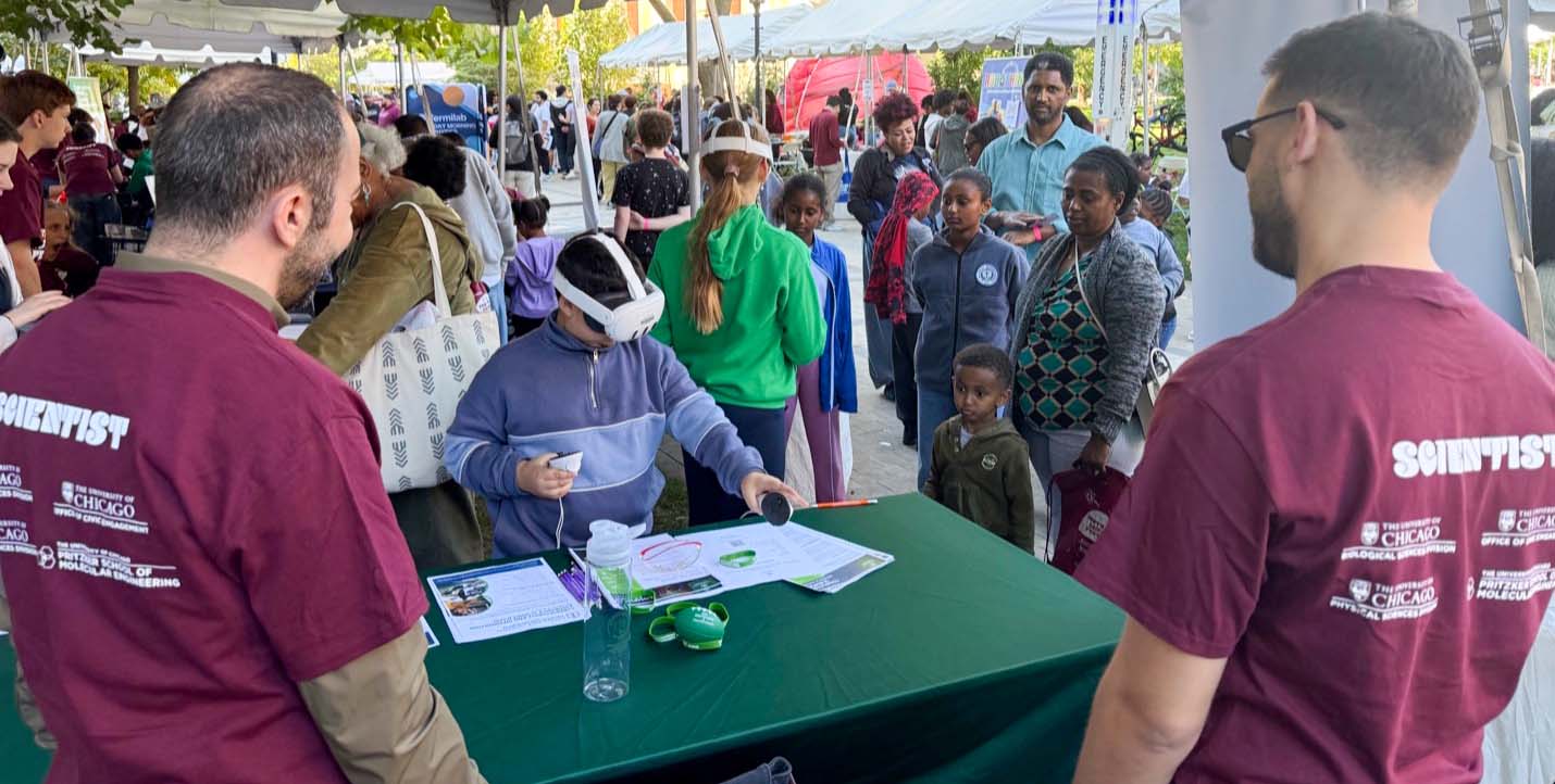 Two volunteers for South Side Science Festival watch as a child tries out a virtual reality headset.