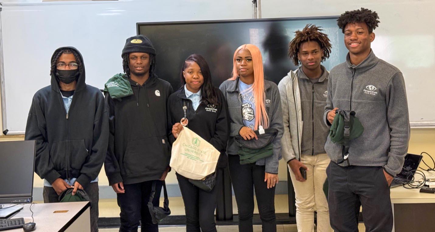A group of six students stand together for a photo holding Chicago State University branded canvas bags and t-shirts.
