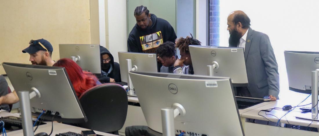 Faculty members and CIMST students assisting high school students in a computer lab.