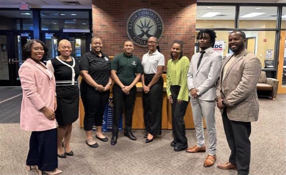 A group of seven adults standing and smiling in the lobby of Elgin Community College