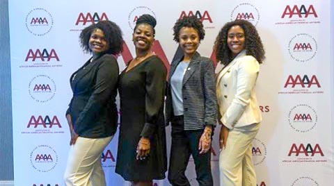 Four women posing together in front of the AAAA conference backdrop