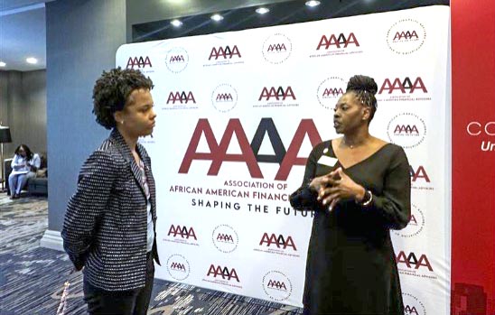 Lisa Pratt, Executive Director of the CWE, talks to a student in front of a backdrop for the "Association of African American Financial Advisors (AAAA).