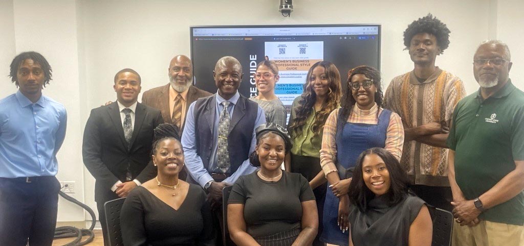 A group of professionals and students posing for a photo in front of a screen displaying a business professional style guide.